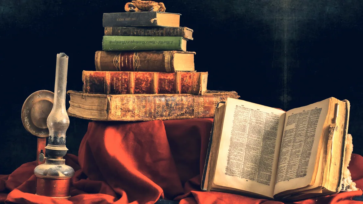 Une pile de vieux livres sous une lampe de lecture.
