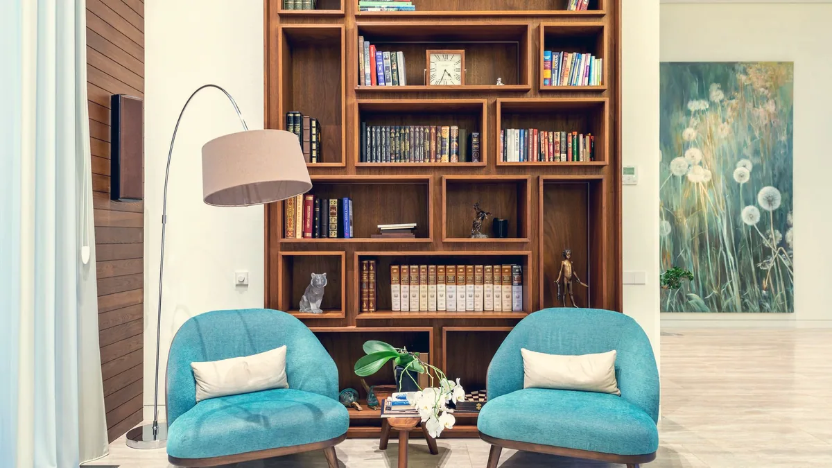Un fauteuil, une lampe et une bibliothèque dans un coin de pièce.