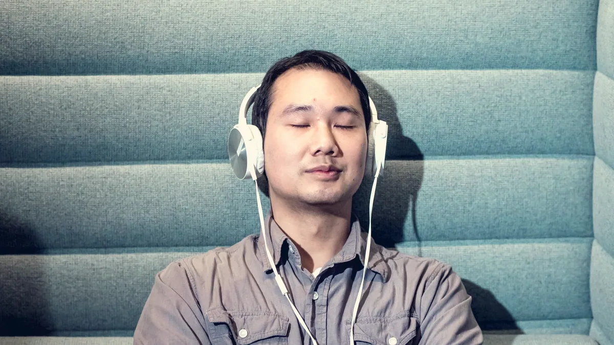 Une personne écoute au casque, les yeux fermés.