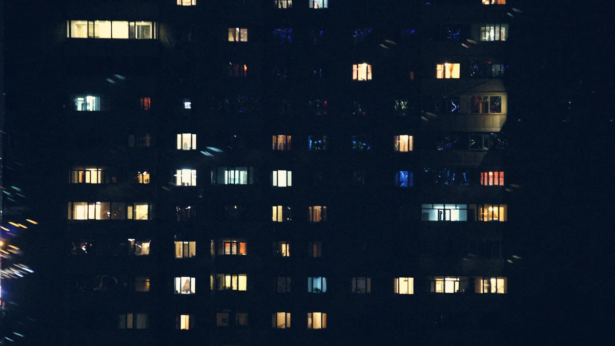 La fenêtre d'un appartement donnant sur une ville la nuit.
