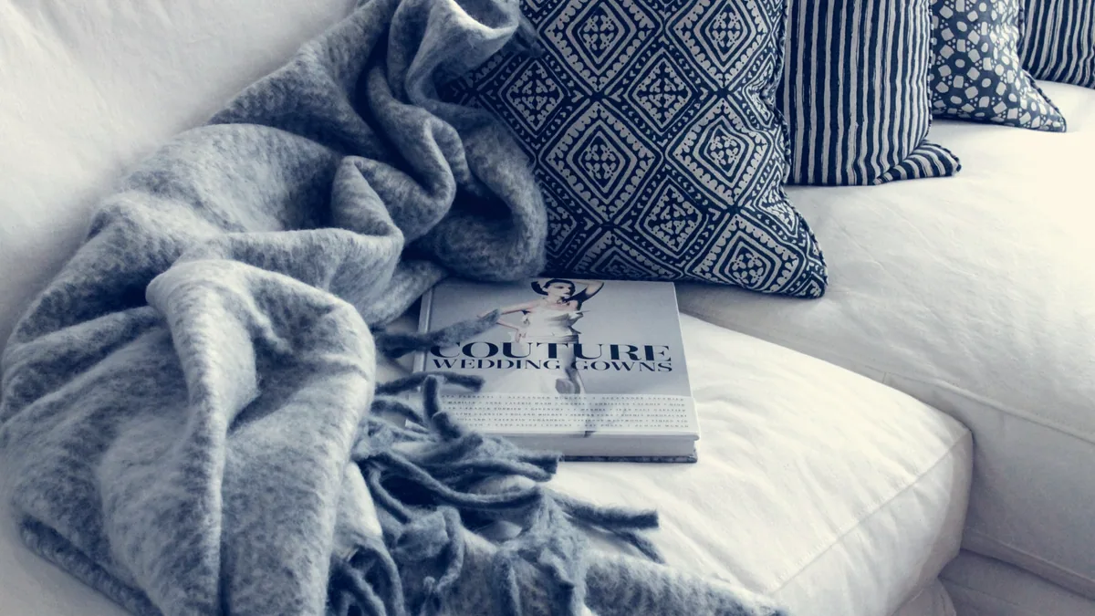 Une couverture et des coussins sur un lit, le soir.