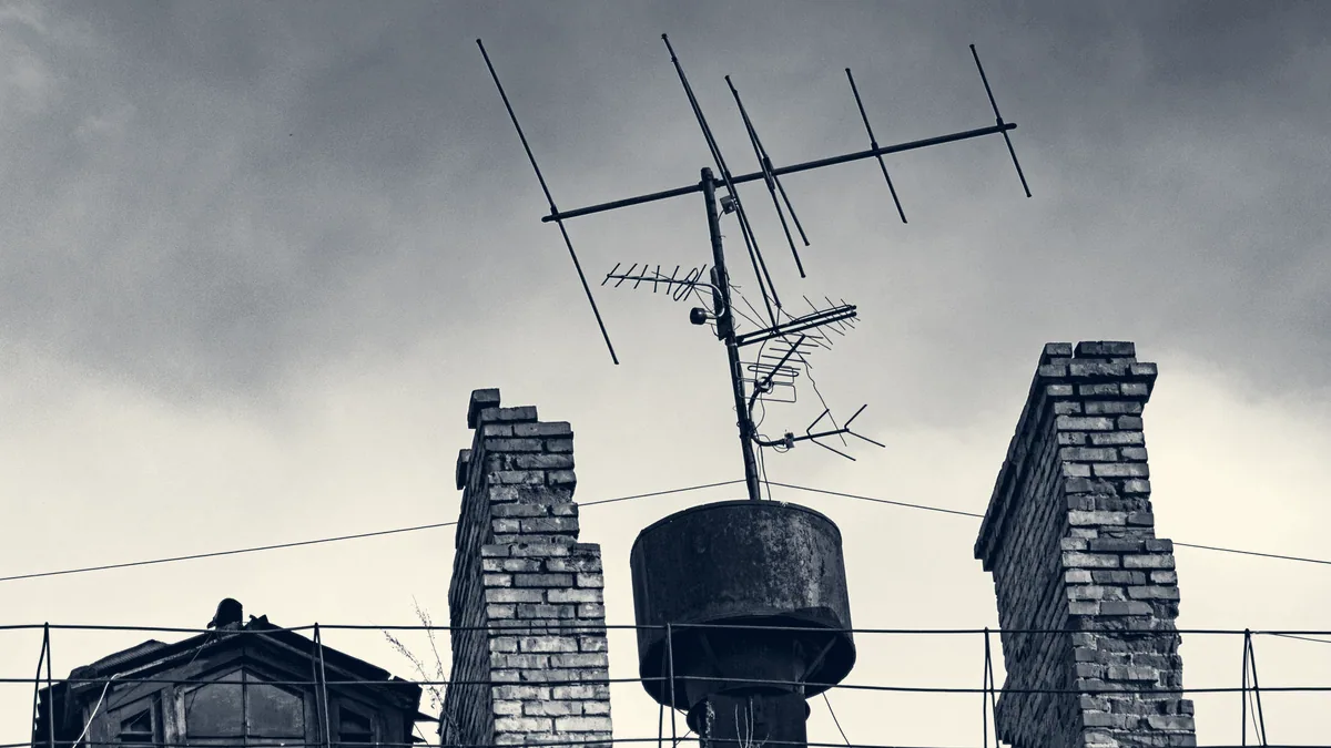 Des antennes de télévision sur les toits, sous un ciel gris.