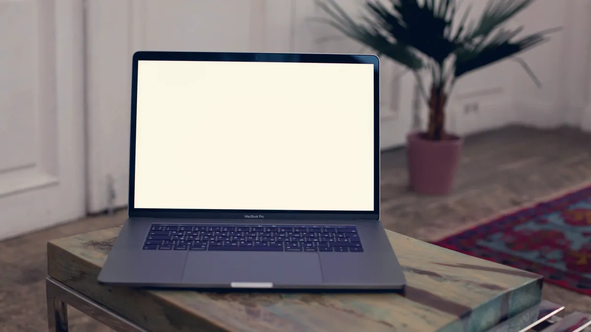 Un ordinateur portable ouvert sur un bureau, écran vide.